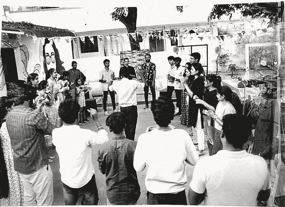 The community standing in a wide circle in a courtyard under a mango tree, bunting overhead.